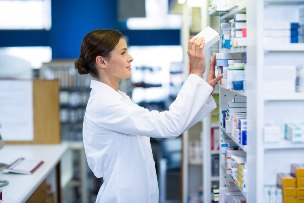 Pharmacist checking medicine in shelf at pharmacy
